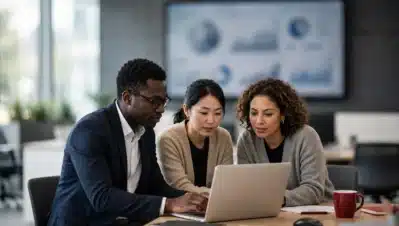 Tres profesionales revisando un informe de ciberseguridad en una laptop en una oficina corporativa